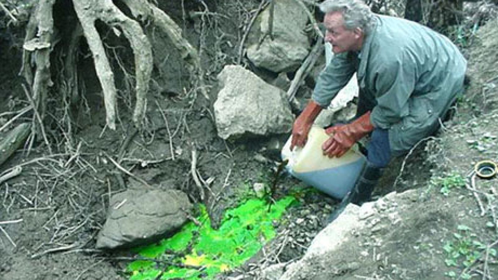 Bénévole versant un liquide traceur dans une perte karstique