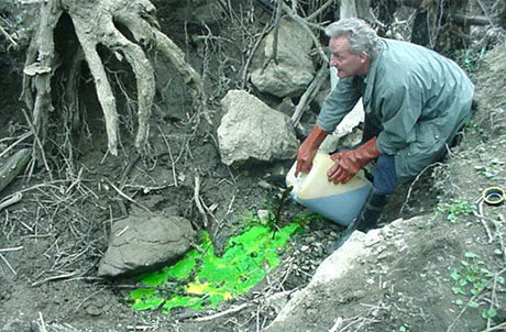 Bénévole versant un liquide traceur dans une perte karstique